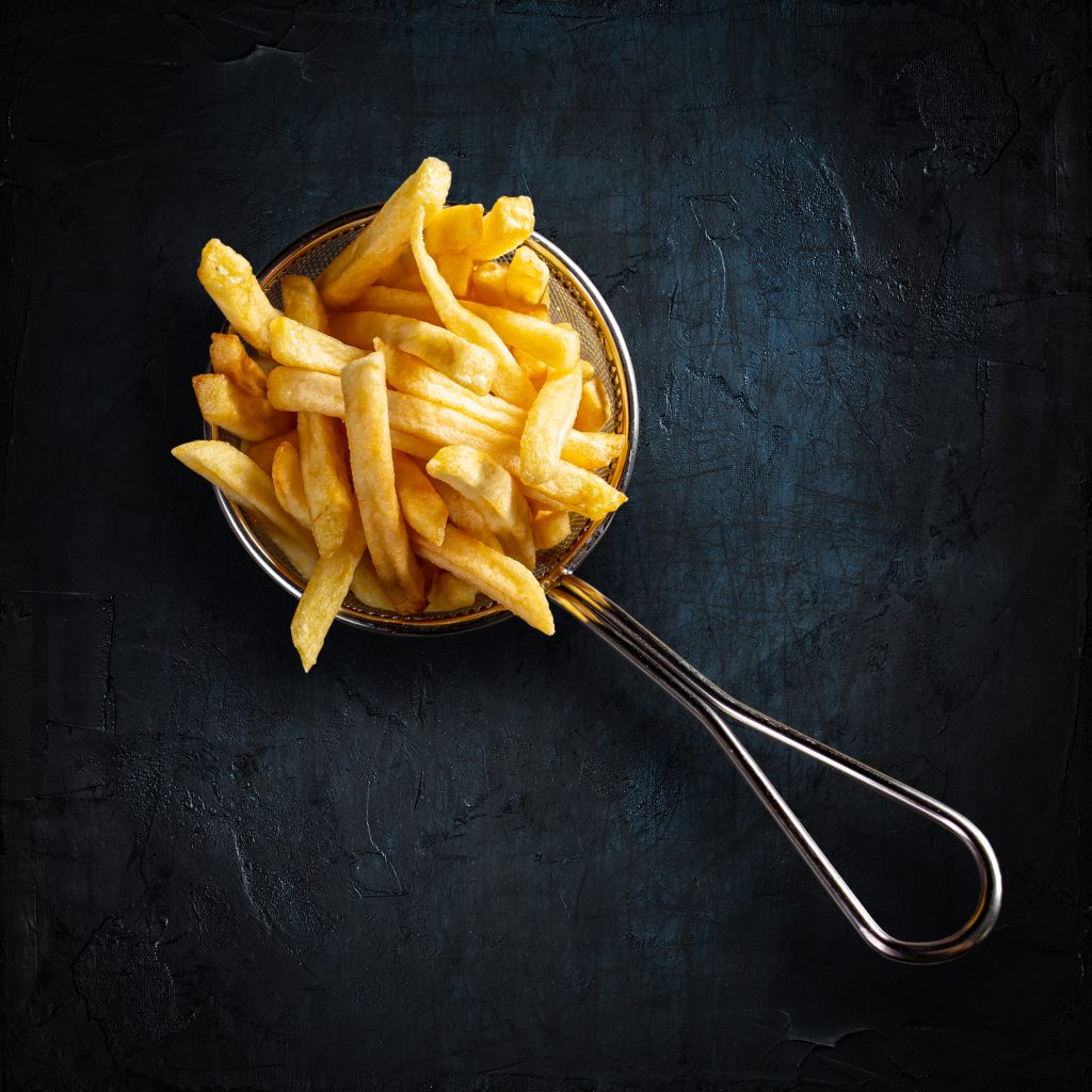 French fries in fancy metal basket on black background. Top view.